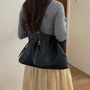 Black leather tote bag with braided strap detail, stylish large shoulder bag for commuting.