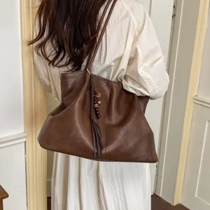 Detail shot of stylish brown leather tote bag with tassel charm, perfect for commute.