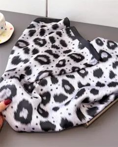 Detailed view of an elegant black and white leopard print silk feel square scarf for women.