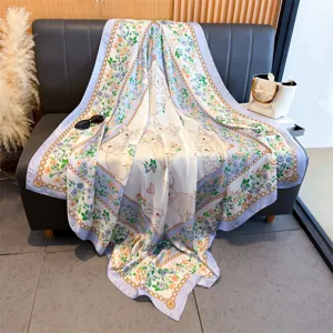 Vue détaillée du foulard carré en soie élégant à motif de fleurs et de lapin sur canapé.