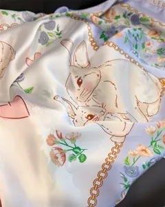 Vue détaillée du foulard en soie avec de jolis motifs de lapins, fleurs et chaînes.