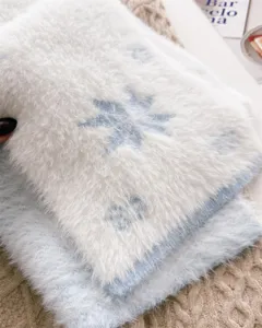 Primer plano detallado de una bufanda de invierno blanca y suave con motivo de copo de nieve.