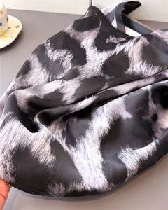 Close-up detail of a chic abstract leopard print silk-like square scarf, soft texture.