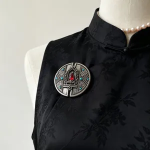 Spilla rotonda tibetana vintage con pietre rosse e turchesi per dettaglio stile etnico.