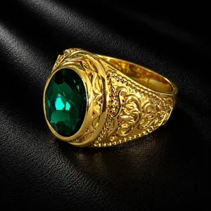 Close-up of a vintage men's gold ring with a large oval green gemstone and ornate carved details.
