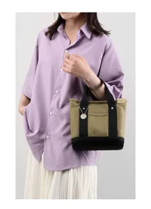 Small canvas tote bag detail featuring durable handles, front pocket and cute pendant.