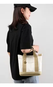 Close-up detail view of the canvas tote bag featuring khaki handles and sturdy design.