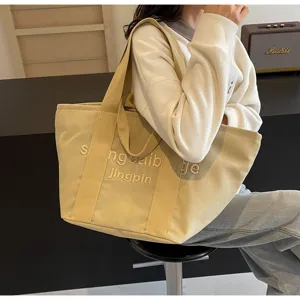 Canvas-Shopper-Detail mit gestickten Buchstaben und stabilen breiten Schulterriemen.
