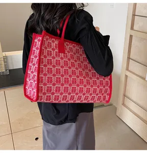 Detail view of a large red knit tote bag featuring a traditional double happiness woven pattern.