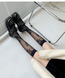 Detailed view of black sheer knee high socks featuring elegant floral jacquard pattern.