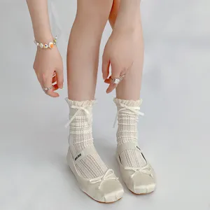 Nahaufnahme von zarten Spitzen-Rüschen-Wadenstrümpfen kombiniert mit Satin-Mary-Janes.