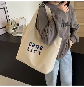 Detailansicht der großen Canvas Umhängetasche mit blauer Stickerei, lässiger Pendlerstil.