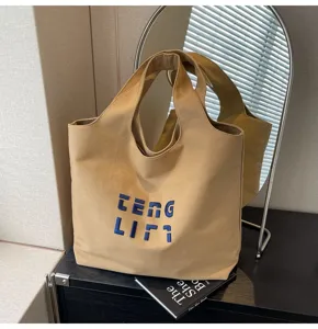 Detailansicht einer stylischen khakifarbenen Segeltuchtasche mit blauer Stickerei.