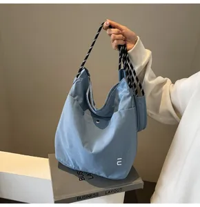 Λεπτομερής λήψη μιας casual γαλάζιας τσάντας tote από νάιλον με ασπρόμαυρα χερούλια.