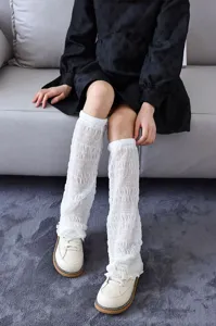 Détail de jambières en dentelle blanche montrant un tissu plissé estival élégant.