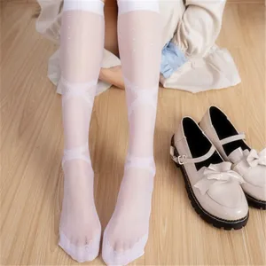 Close-up of white sheer polka dot lace calf socks with cross ribbon design, light summer style.