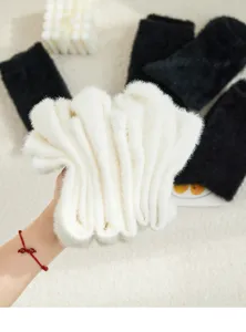 Nahaufnahme der kuscheligen weißen und schwarzen Plüsch-Wintersocken mit weicher Textur.