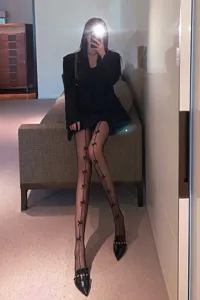 Black fishnet pantyhose featuring vertical bow details, chic dark style legwear for women.