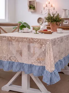Detailed view of pastoral crochet lace tablecloth with blue and white checkered ruffle edge.