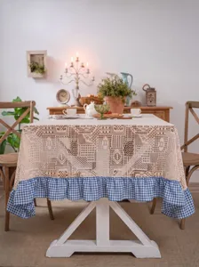 Detailed view of pastoral crochet lace tablecloth with blue and white check ruffle trim.
