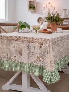 Detailed view of pastoral crochet lace tablecloth with green checkered ruffled hem, rustic decor.