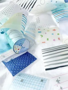 Ruban adhésif washi bleu et rouleaux d'autocollants en papier sulfurisé avec motifs dorés.