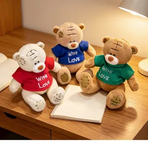 Detailed shot of cute plush teddy bear toys wearing colorful sweaters on a wooden desk.