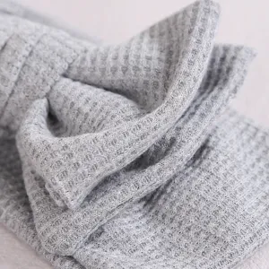 Vue détaillée du bandeau bébé en tricot gaufré gris, accessoire de cheveux doux.