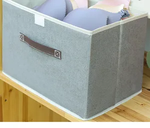 Dettaglio scatola portaoggetti in tessuto grigio con materiale effetto lino e comoda manico.