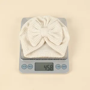 Newborn baby knit bow hat detail shot, cute infant turban beanie in beige color.