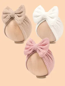 Close-up detail of cute newborn knitted bow beanie hats displaying soft fabric and colors.
