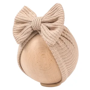 Close-up view of the cute baby knitted hat featuring a large elegant bow in soft beige color.