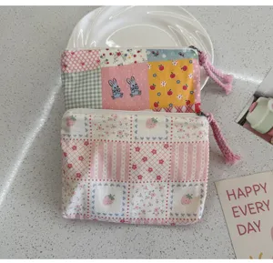 Cute canvas cosmetic pouch detail showing delicate patchwork floral patterns and zipper pull.