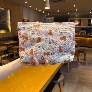 Cute pink cosmetic bag detail view with charming puppy pattern and woven fabric label.