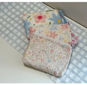 Close-up detail shot of cute floral print fabric storage pouch with zipper and tassel pull.
