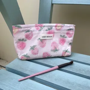 Primo piano della borsa cosmetica rosa con stampa di fragole e etichetta bianca.