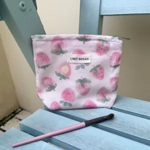 Primo piano dettagliato della graziosa trousse trucco rosa fragola con etichetta di marca.