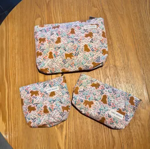 Detailed view of cute pink puppy print cosmetic pouch showing zipper closure and brand label.