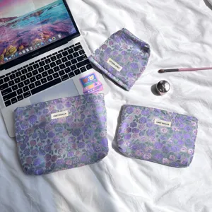 Vista dettagliata del set di borse cosmetiche con fiori viola su sfondo in tessuto bianco.