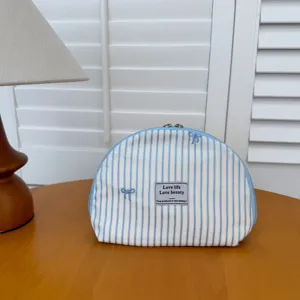 Blue striped cosmetic bag with cute embroidered bows, portable shell makeup pouch for travel.
