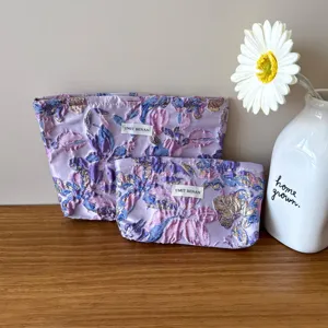 Primo piano sui dettagli e motivi floreali del set di borse cosmetiche jacquard vintage.
