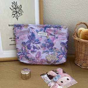 Vista dettagliata della borsa cosmetica in jacquard floreale viola su tavolo.