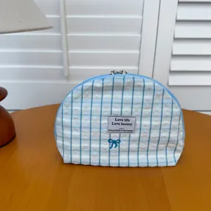 Detail view of the blue and white striped cosmetic pouch featuring cute bow embroidery tag.