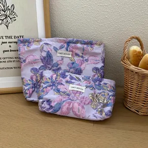 Pochette cosmetica viola in jacquard floreale con chiusura a zip ed etichetta tessuta.