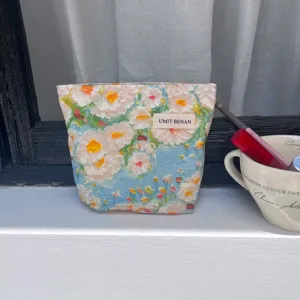 Detail view of portable oil painting floral cosmetic pouch, soft fabric makeup storage bag.