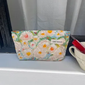 Detailed view of floral makeup pouch featuring oil painting print and branded woven tag.