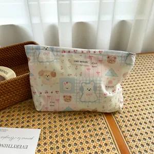 Detailed view of the cute rabbit and bear print cosmetic pouch with woven label on rattan table.