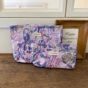 Dettaglio borsa cosmetica jacquard viola chiaro, trama floreale vintage e tessuto.
