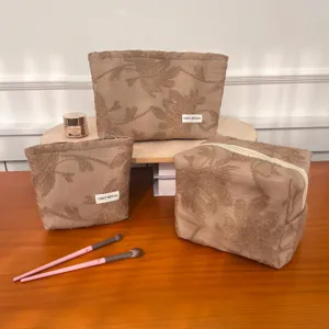 Close-up of vintage linen floral embroidered cosmetic bags set, displaying textured fabric.