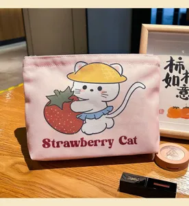 Détail de la trousse de toilette en toile avec motif de chat mignon et de fraise sur bureau.
